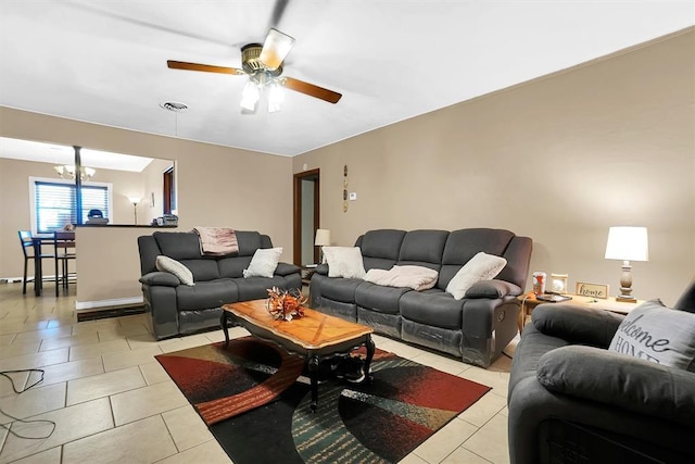 living room featuring light tile patterned flooring and ceiling fan with notable chandelier