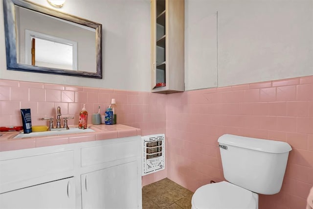 bathroom with vanity, heating unit, tile walls, tile patterned flooring, and toilet