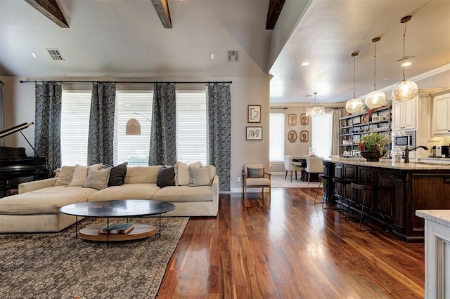 living room featuring sink, dark hardwood / wood-style flooring, lofted ceiling with beams, crown molding, and a chandelier