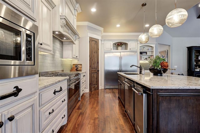 kitchen featuring hanging light fixtures, built in appliances, an island with sink, dark hardwood / wood-style flooring, and white cabinetry