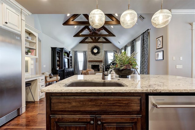 kitchen with sink, dark hardwood / wood-style floors, stainless steel built in refrigerator, decorative light fixtures, and a kitchen island with sink