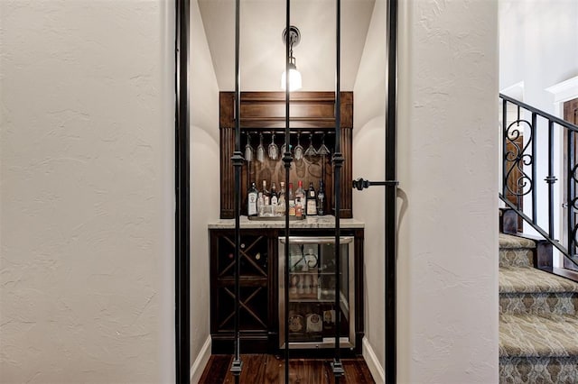 wine room featuring wine cooler, dark hardwood / wood-style flooring, and bar