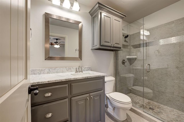 bathroom featuring ceiling fan, a shower with door, vanity, and toilet