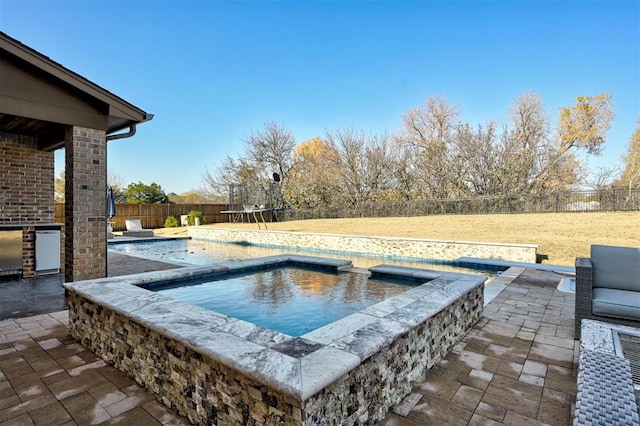 view of pool with an in ground hot tub, a patio, a trampoline, and area for grilling