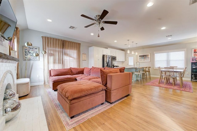 living room with ceiling fan, light wood-type flooring, sink, and vaulted ceiling