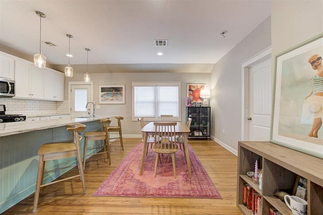 dining area with sink and light hardwood / wood-style floors