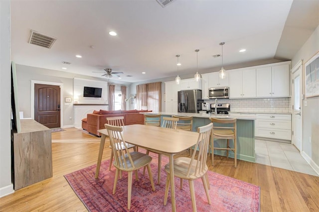 dining space featuring ceiling fan, light wood-type flooring, and sink