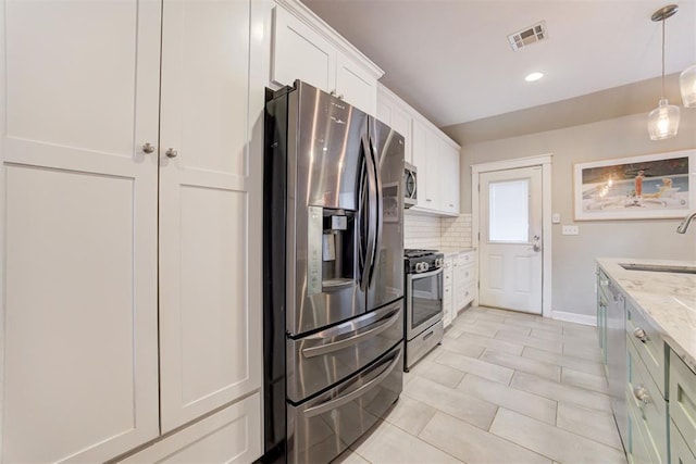 kitchen featuring light stone countertops, sink, stainless steel appliances, decorative light fixtures, and white cabinets