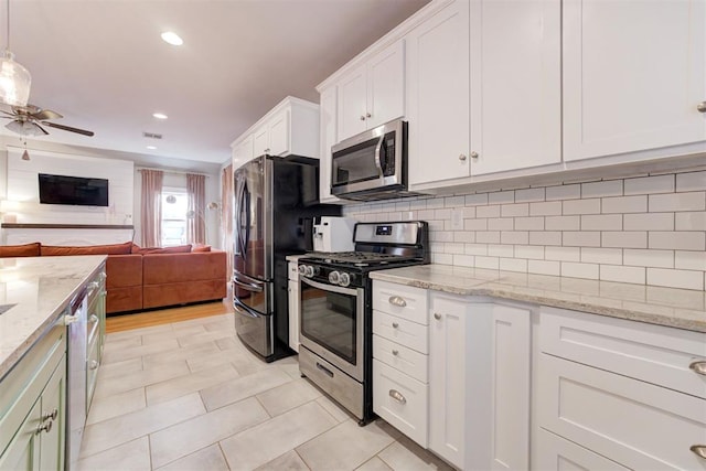 kitchen featuring light stone countertops, appliances with stainless steel finishes, backsplash, white cabinetry, and hanging light fixtures