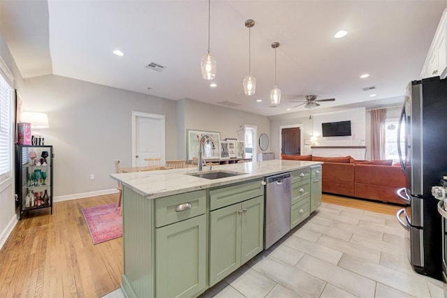 kitchen featuring appliances with stainless steel finishes, light wood-type flooring, ceiling fan, sink, and a center island with sink