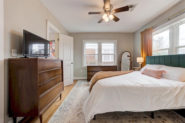 bedroom featuring ceiling fan, light wood-type flooring, and multiple windows