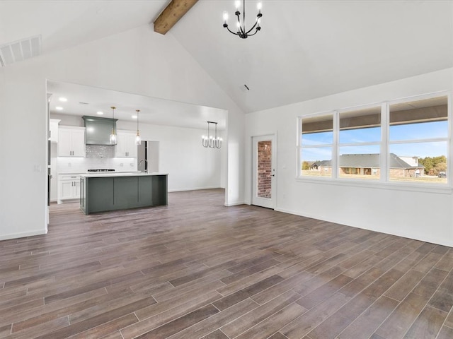 unfurnished living room featuring beamed ceiling, dark hardwood / wood-style floors, high vaulted ceiling, and a notable chandelier