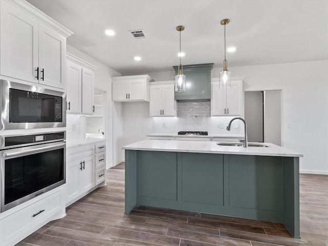 kitchen featuring dark hardwood / wood-style floors, white cabinetry, stainless steel appliances, and hanging light fixtures