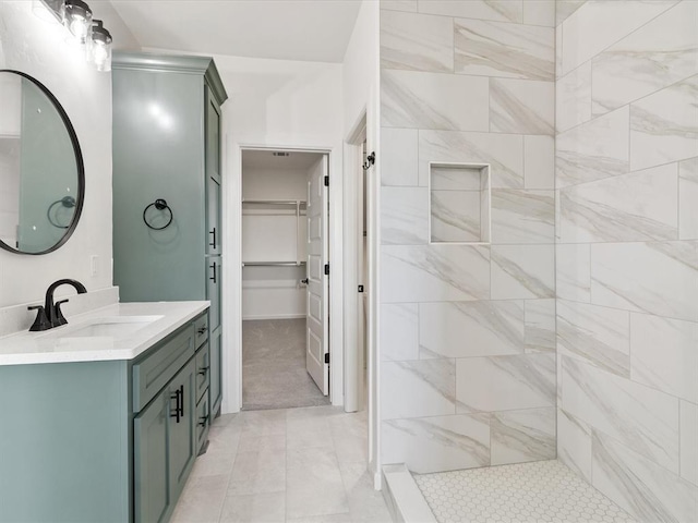 bathroom with a tile shower and vanity