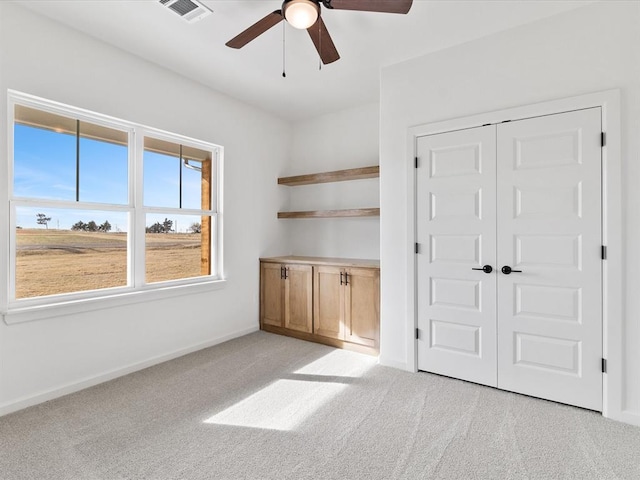 unfurnished bedroom featuring light carpet, a closet, and ceiling fan