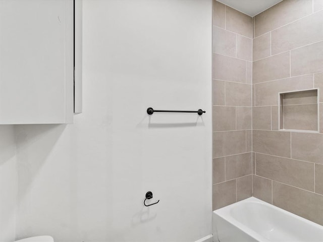 bathroom with tiled shower / bath combo and toilet