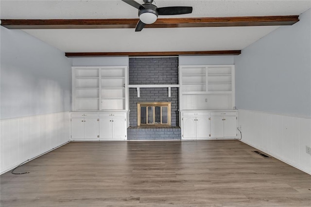 unfurnished living room featuring a fireplace, light hardwood / wood-style flooring, beamed ceiling, and built in features