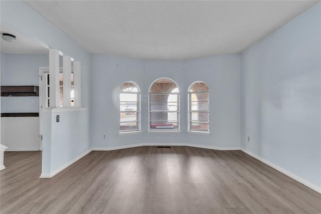 empty room featuring a textured ceiling and light wood-type flooring