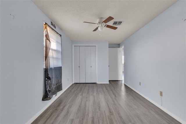 unfurnished bedroom with hardwood / wood-style flooring, ceiling fan, a textured ceiling, and a closet