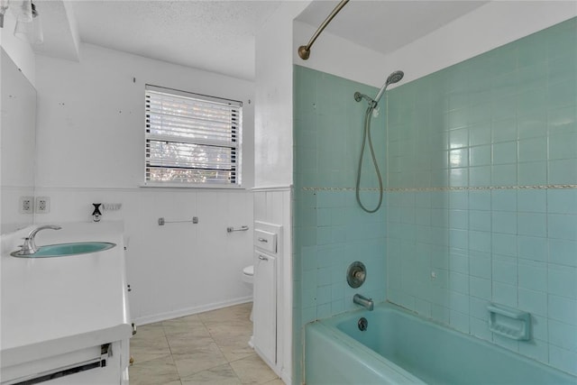 full bathroom featuring a textured ceiling, vanity, tiled shower / bath combo, and toilet