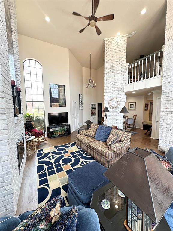 living room featuring ceiling fan with notable chandelier, a high ceiling, and hardwood / wood-style flooring