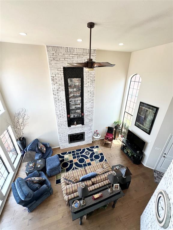 living room with hardwood / wood-style floors, a large fireplace, and ceiling fan