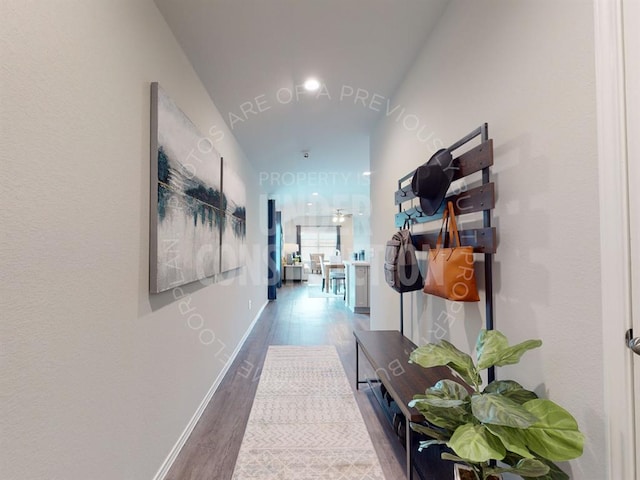 corridor with hardwood / wood-style flooring and vaulted ceiling