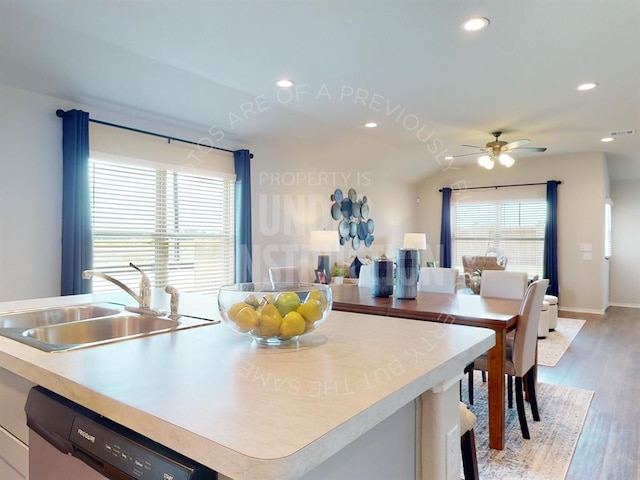 kitchen with dishwasher, a kitchen island with sink, sink, vaulted ceiling, and light hardwood / wood-style flooring