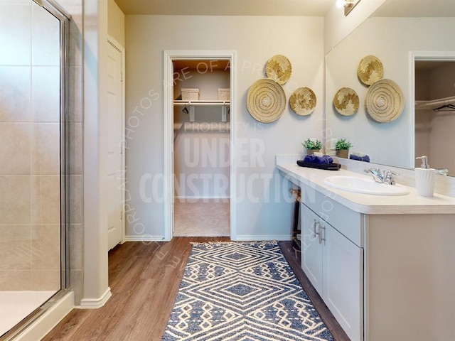 bathroom with hardwood / wood-style floors, vanity, and an enclosed shower