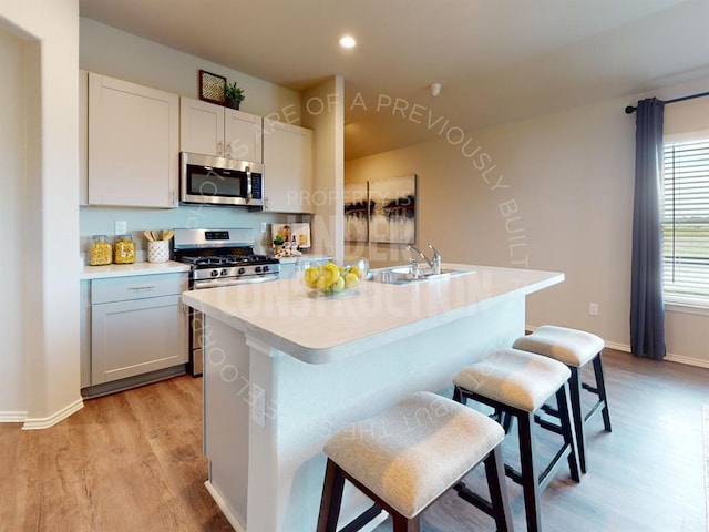 kitchen with a breakfast bar area, a kitchen island with sink, sink, and stainless steel appliances