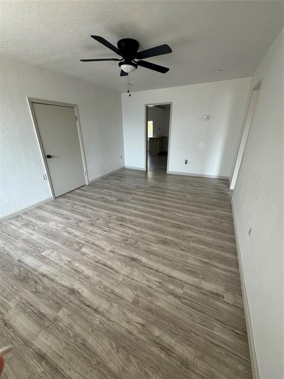 empty room with a textured ceiling, hardwood / wood-style flooring, and ceiling fan