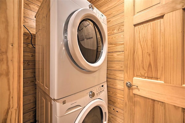 laundry area featuring stacked washer / dryer and wooden walls