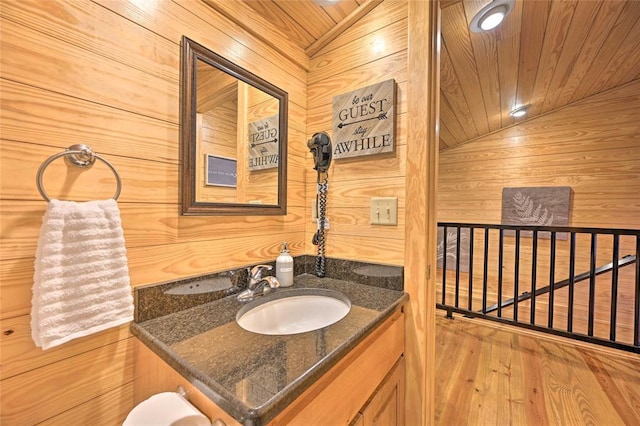 bathroom with wood walls, wood-type flooring, and vaulted ceiling