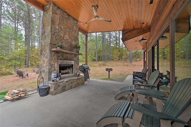 view of patio with an outdoor stone fireplace, ceiling fan, and a grill