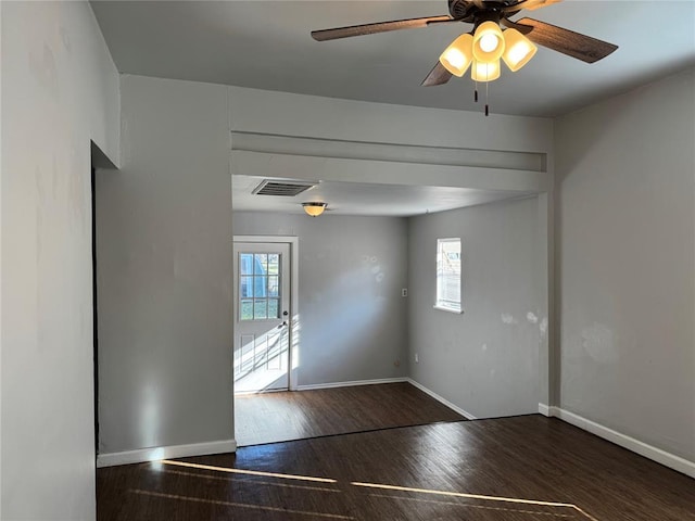 spare room featuring ceiling fan, a healthy amount of sunlight, and dark hardwood / wood-style flooring