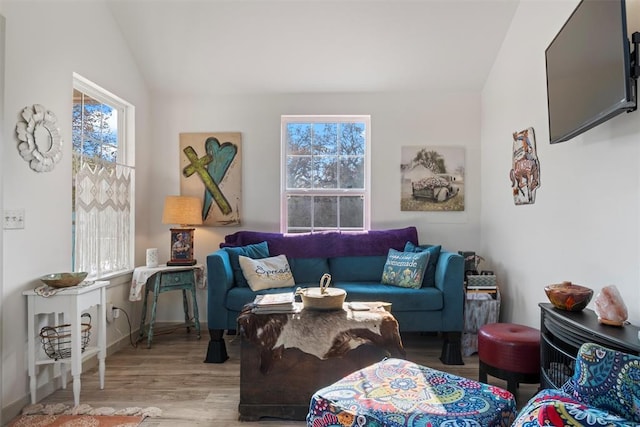 living room with plenty of natural light, light wood-type flooring, and vaulted ceiling