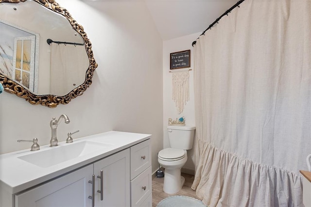 bathroom featuring vanity, toilet, lofted ceiling, and wood-type flooring