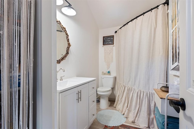 bathroom with vanity, toilet, and vaulted ceiling