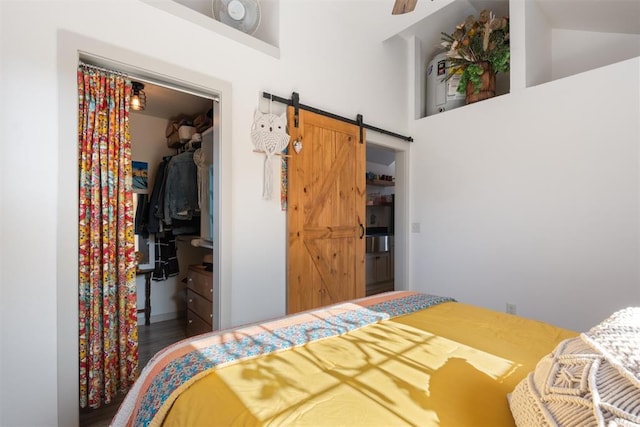 bedroom featuring a spacious closet, a barn door, high vaulted ceiling, hardwood / wood-style floors, and a closet