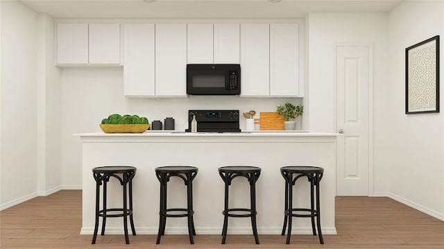 kitchen featuring black appliances, light wood-type flooring, white cabinetry, and a breakfast bar area