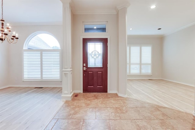 foyer entrance with light hardwood / wood-style floors, crown molding, and a chandelier