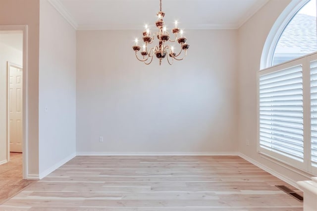 empty room featuring a notable chandelier, light wood-type flooring, and a wealth of natural light