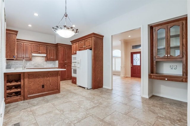 kitchen with kitchen peninsula, tasteful backsplash, white appliances, decorative light fixtures, and an inviting chandelier