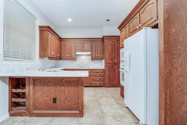 kitchen with tasteful backsplash, kitchen peninsula, sink, and white appliances