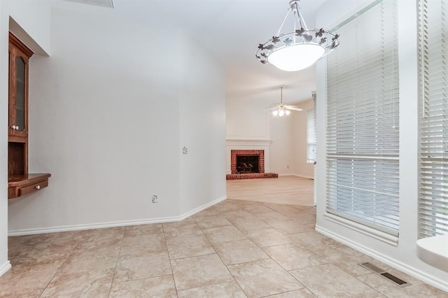 unfurnished living room featuring light tile patterned floors, a brick fireplace, and ceiling fan