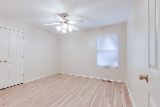 empty room with ceiling fan and light hardwood / wood-style floors