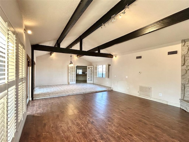 unfurnished living room featuring a textured ceiling, vaulted ceiling with beams, a stone fireplace, and dark wood-type flooring