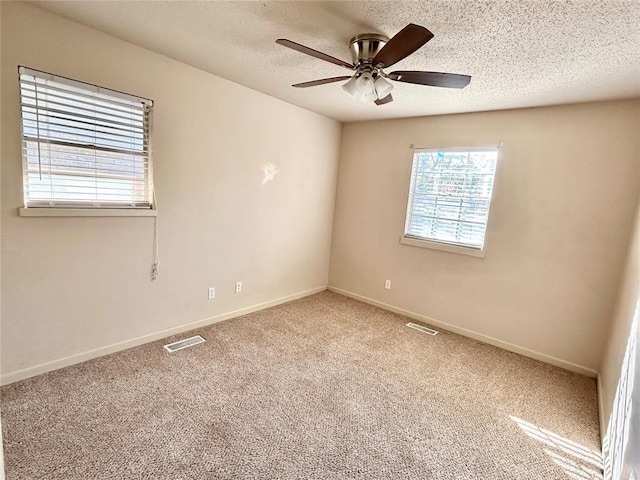 carpeted spare room with ceiling fan and a textured ceiling