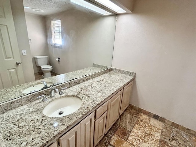 bathroom with a textured ceiling, vanity, and toilet