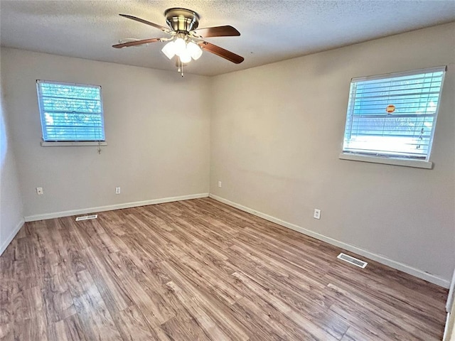 unfurnished room with hardwood / wood-style floors, ceiling fan, and a textured ceiling